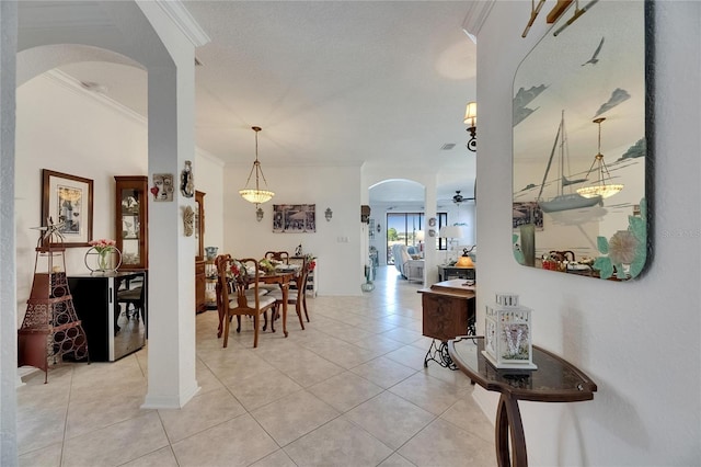 dining room featuring arched walkways, ornamental molding, and light tile patterned flooring