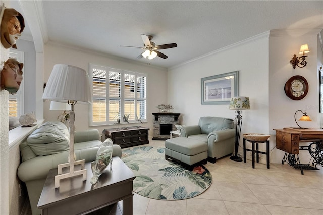 living area with light tile patterned floors, ornamental molding, a ceiling fan, and a stone fireplace