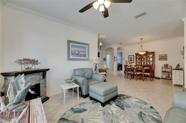 living room with visible vents, crown molding, ceiling fan, arched walkways, and light tile patterned floors