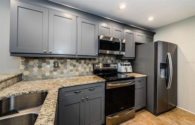 124 Nina Way Unit 24, Oldsmar, FL 34677 - kitchen featuring stainless steel appliances, backsplash, a sink, light stone counters, and gray cabinets