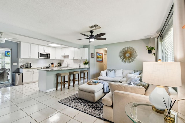 1751 Ashton Abbey Rd, Clearwater, FL 33755 - living area featuring a ceiling fan, healthy amount of natural light, light tile patterned floors, and a textured ceiling