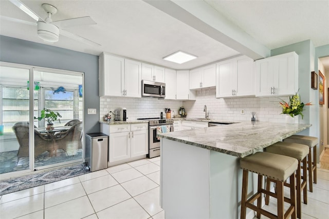 1751 Ashton Abbey Rd, Clearwater, FL 33755 - kitchen featuring stainless steel appliances, light stone counters, a peninsula, backsplash, and white cabinetry