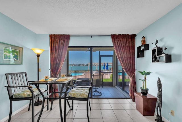 6279 Sun Blvd Unit 103, Saint Petersburg, FL 33715 - dining space featuring a water view, a textured ceiling, baseboards, and light tile patterned floors