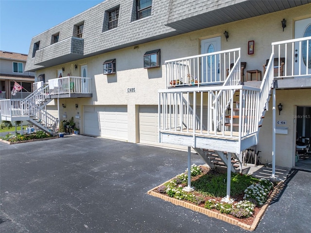 12485 2nd St E Unit C103, Treasure Island, FL 33706 - view of property with stairway, asphalt driveway, and a garage