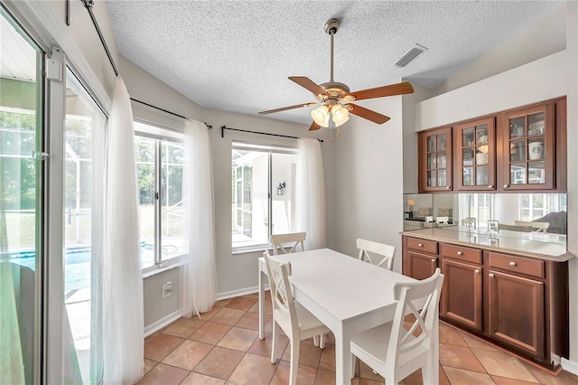 dining room with a ceiling fan, light tile patterned flooring, a textured ceiling, and visible vents