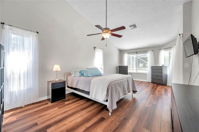 bedroom with a textured ceiling, wood finished floors, visible vents, and lofted ceiling