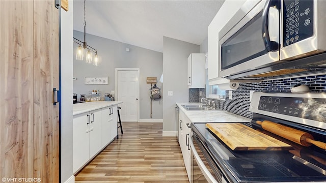 kitchen with a sink, decorative backsplash, white cabinets, and appliances with stainless steel finishes