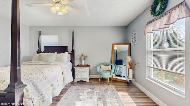 bedroom featuring baseboards, a ceiling fan, a textured ceiling, and wood finished floors