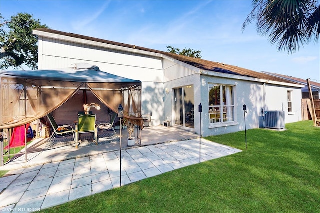 back of property featuring a gazebo, a patio area, stucco siding, a lawn, and central AC unit