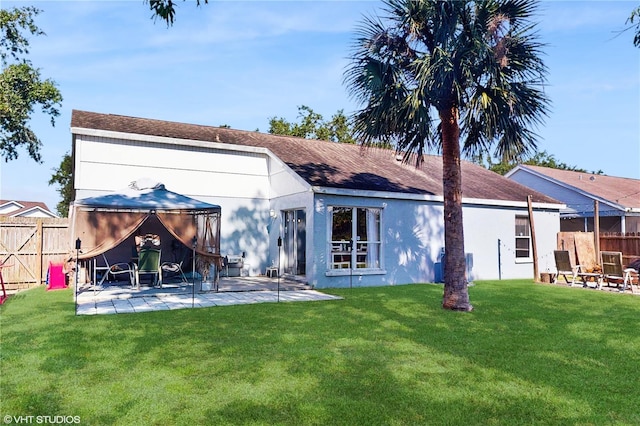 back of property featuring a yard, a patio, a gazebo, and fence