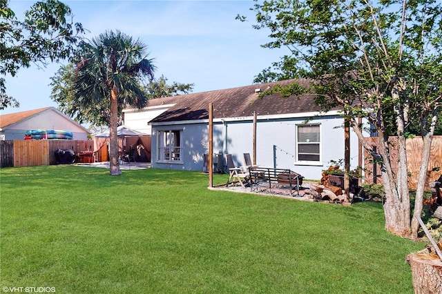 back of property with roof with shingles, a patio, stucco siding, a fenced backyard, and a lawn