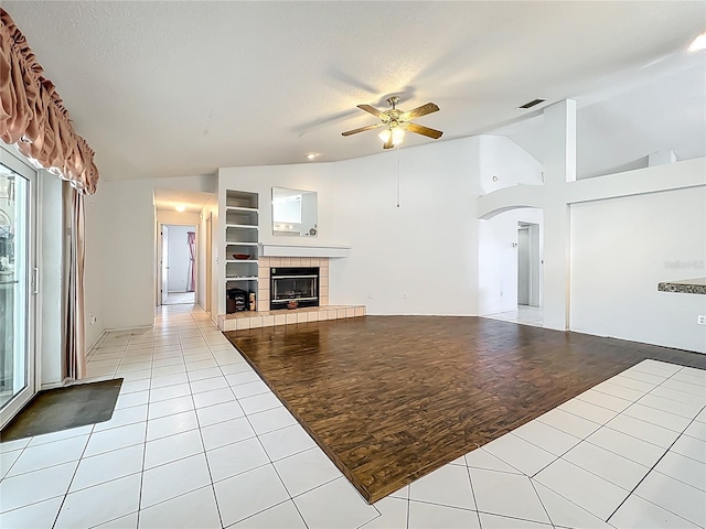 11216 Longbrooke Dr, Riverview, FL 33579 - unfurnished living room with lofted ceiling, a ceiling fan, arched walkways, light tile patterned floors, and a tile fireplace