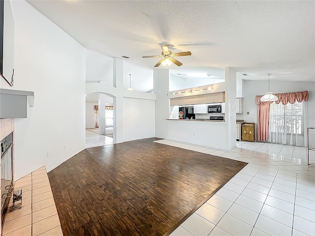 11216 Longbrooke Dr, Riverview, FL 33579 - unfurnished living room with a ceiling fan, arched walkways, vaulted ceiling, a tile fireplace, and light tile patterned flooring