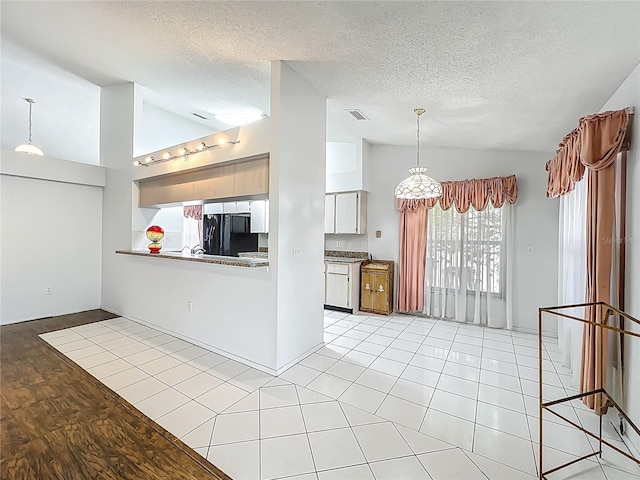 11216 Longbrooke Dr, Riverview, FL 33579 - kitchen with refrigerator, lofted ceiling, a textured ceiling, white cabinets, and decorative light fixtures