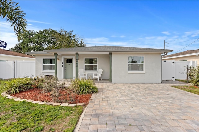 view of front of property featuring fence, stucco siding, and a porch