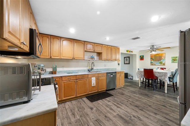 kitchen featuring wood finished floors, a sink, stainless steel appliances, light countertops, and visible vents
