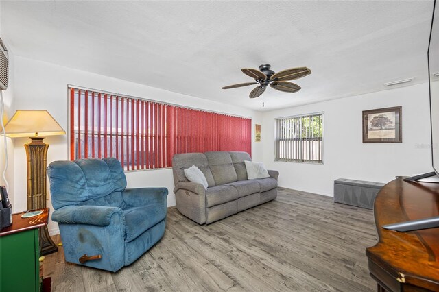 living room featuring visible vents, baseboards, a ceiling fan, and wood finished floors