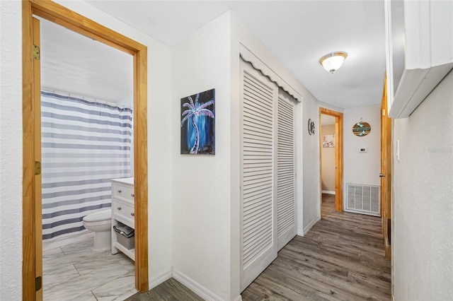 hallway featuring visible vents and baseboards