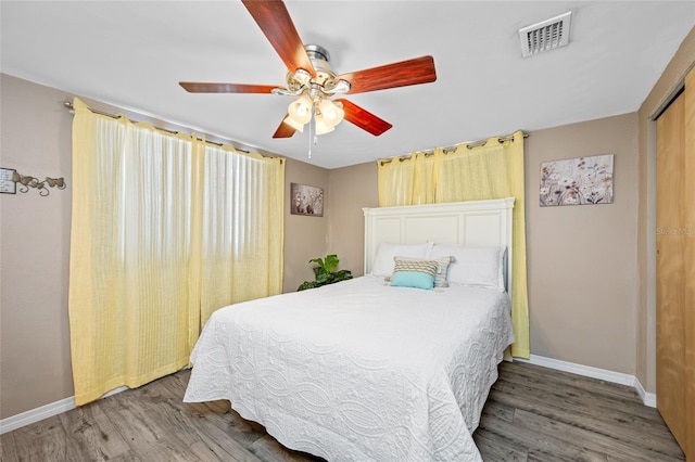 bedroom featuring baseboards, visible vents, a ceiling fan, wood finished floors, and a closet