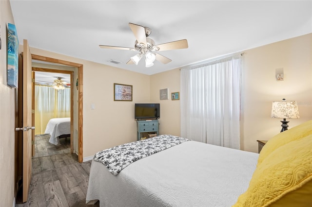 bedroom featuring wood finished floors, visible vents, baseboards, and ceiling fan