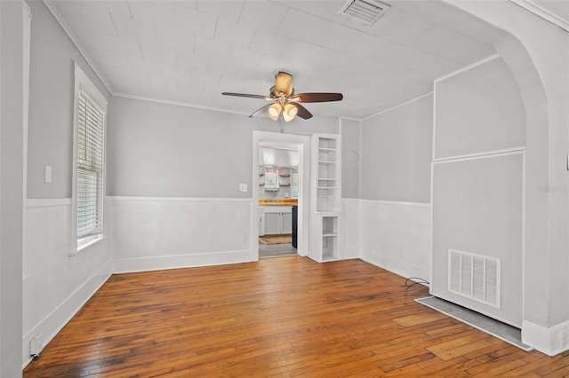 2450 3rd Ave N, Saint Petersburg, FL 33713 - unfurnished room featuring crown molding, hardwood / wood-style flooring, wainscoting, a ceiling fan, and arched walkways