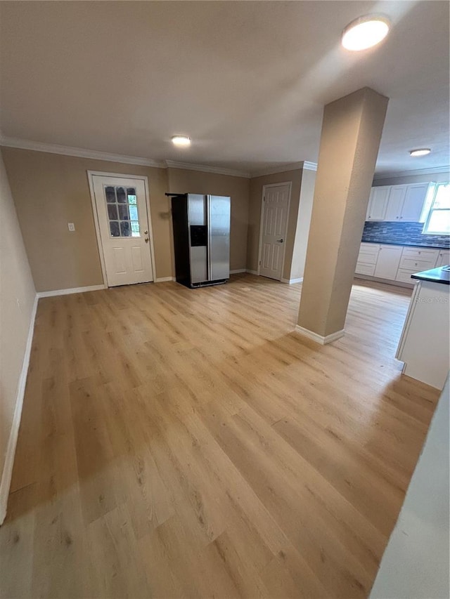 unfurnished living room with crown molding, baseboards, and light wood-style flooring