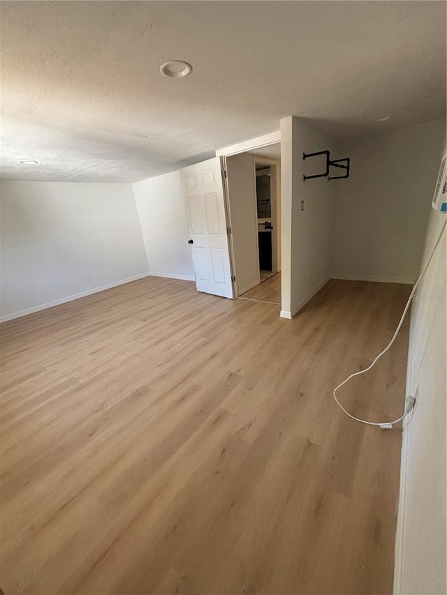 interior space featuring baseboards, a textured ceiling, and light wood-style flooring