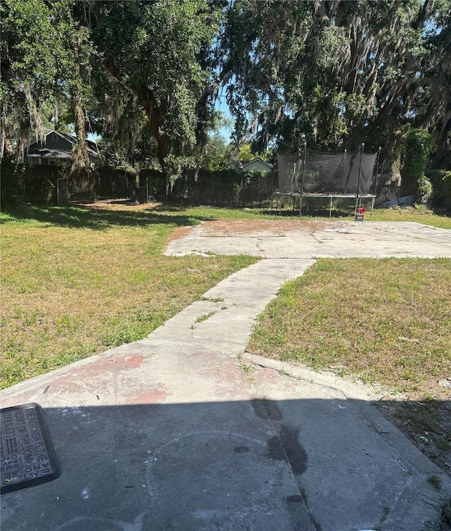 view of yard featuring a trampoline and fence