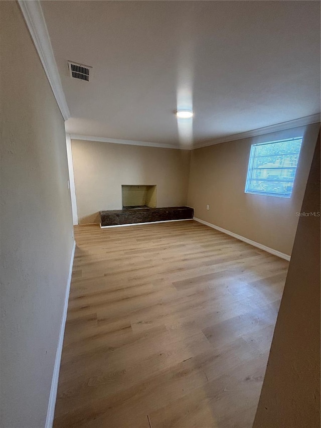 basement with visible vents, baseboards, crown molding, and wood finished floors