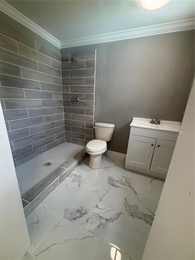 full bathroom with vanity, ornamental molding, marble finish floor, toilet, and a tile shower