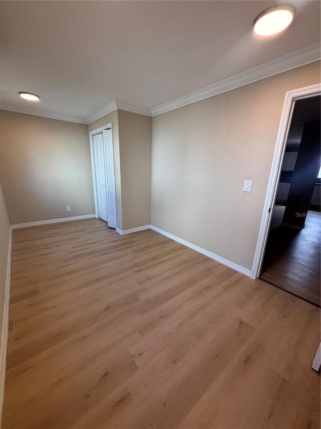 unfurnished room featuring crown molding, baseboards, and wood finished floors