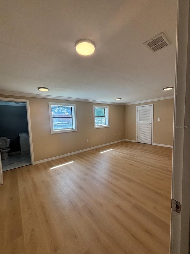 unfurnished room with crown molding, baseboards, visible vents, and light wood-type flooring