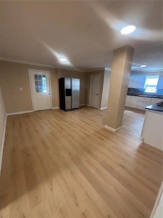 interior space with baseboards, ornamental molding, light wood finished floors, and a wealth of natural light