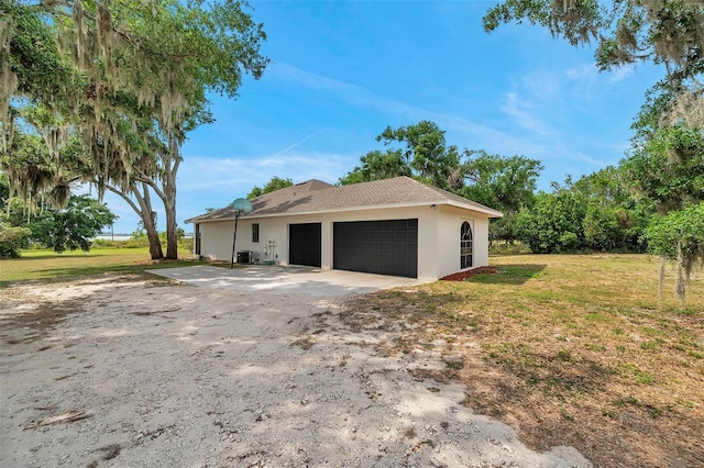 view of side of home with a yard, an attached garage, central AC unit, and stucco siding