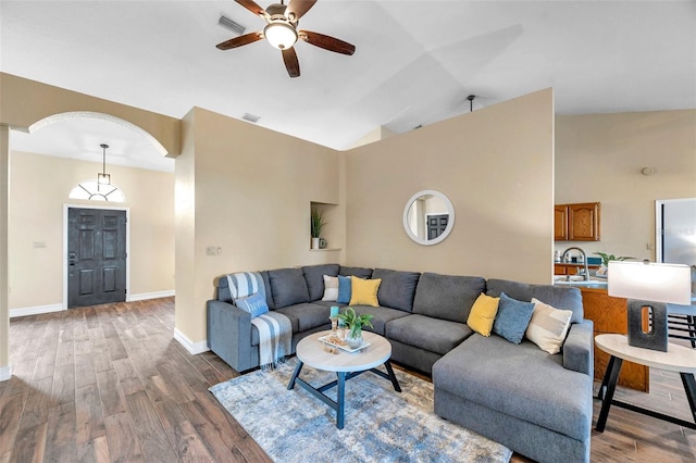 living area featuring visible vents, baseboards, lofted ceiling, a ceiling fan, and wood finished floors