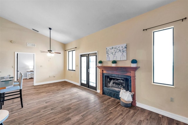 unfurnished living room with vaulted ceiling, wood finished floors, visible vents, and baseboards