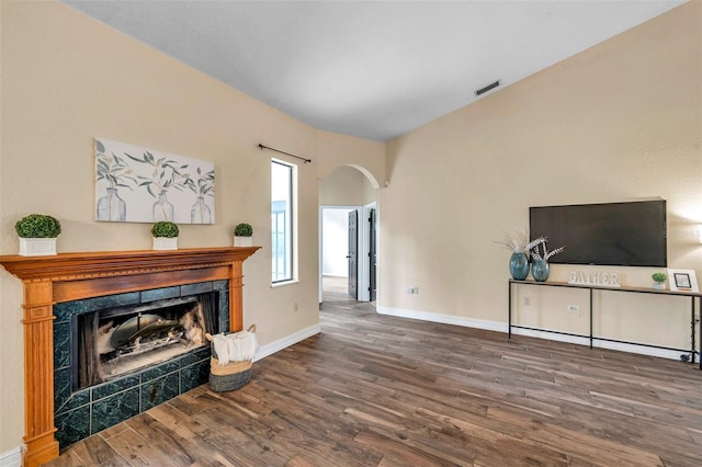 unfurnished living room featuring arched walkways, visible vents, baseboards, a premium fireplace, and wood finished floors