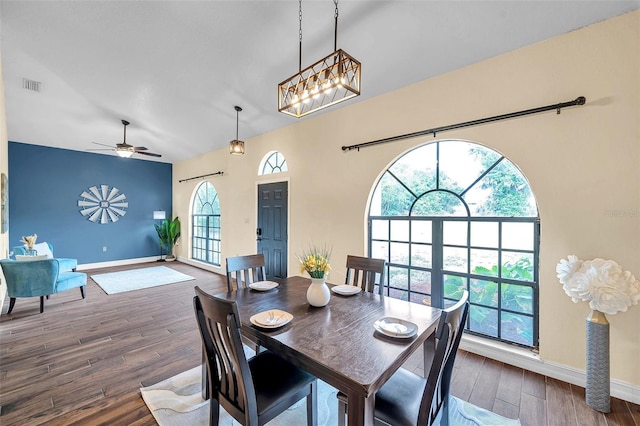 dining area featuring ceiling fan with notable chandelier, baseboards, wood finished floors, and visible vents