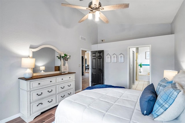 bedroom featuring light wood finished floors, ensuite bathroom, visible vents, a ceiling fan, and high vaulted ceiling