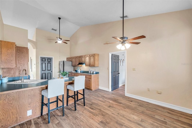 kitchen with light wood-style flooring, a sink, baseboards, freestanding refrigerator, and a ceiling fan