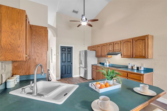 kitchen with a sink, brown cabinets, ceiling fan, stainless steel fridge with ice dispenser, and under cabinet range hood