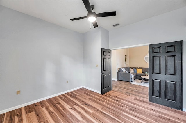 empty room with light wood finished floors, baseboards, a ceiling fan, and visible vents