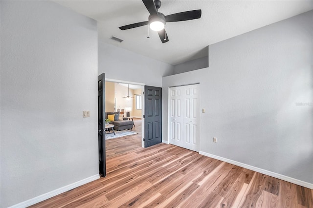 unfurnished bedroom with light wood finished floors, vaulted ceiling, visible vents, a closet, and baseboards