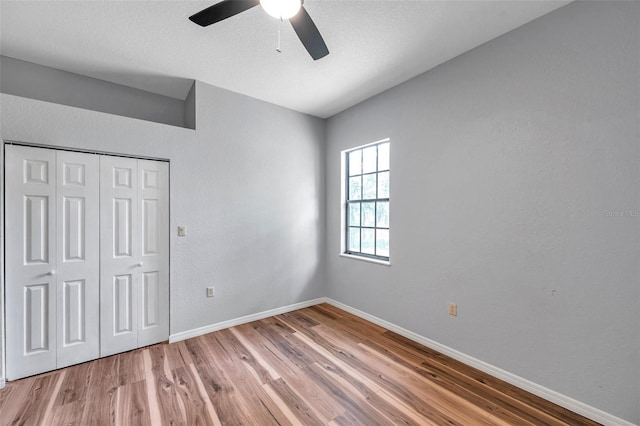 unfurnished bedroom with baseboards, a ceiling fan, wood finished floors, and a closet
