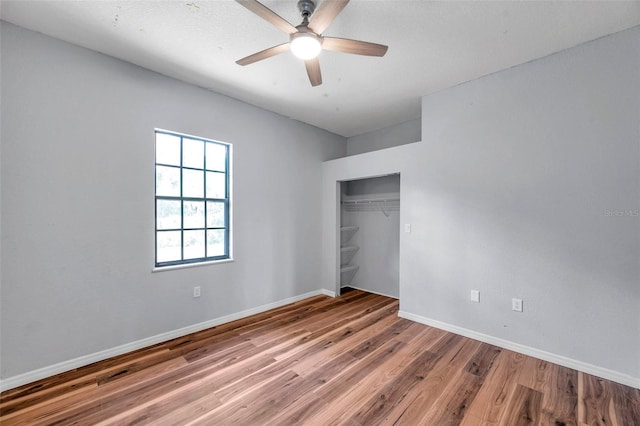 unfurnished bedroom with baseboards, a ceiling fan, wood finished floors, and a closet