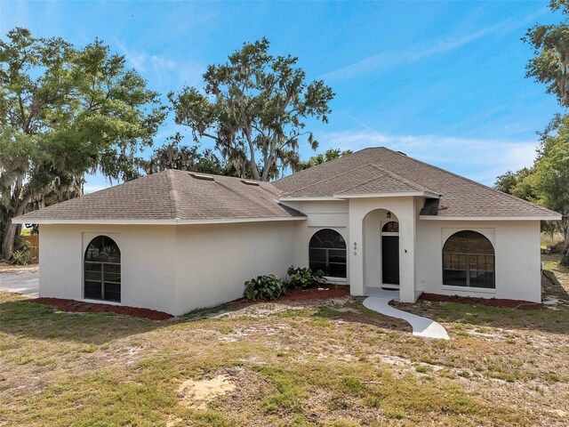 view of front of home featuring a shingled roof, a front lawn, and stucco siding
