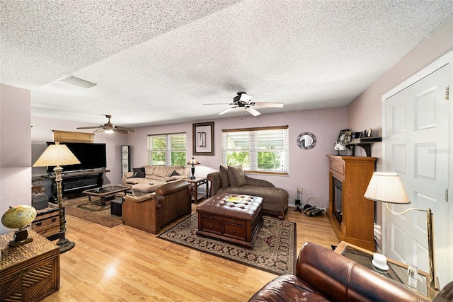 1399 Leeward Ave, Spring Hill, FL 34606 - living area with ceiling fan, a glass covered fireplace, a textured ceiling, and visible vents