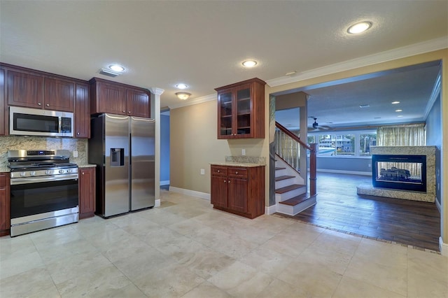 5449 Manatee Point Dr, New Port Richey, FL 34652 - kitchen with appliances with stainless steel finishes, crown molding, decorative backsplash, glass insert cabinets, and ceiling fan