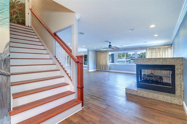 5449 Manatee Point Dr, New Port Richey, FL 34652 - stairway featuring a multi sided fireplace, ornamental molding, a ceiling fan, wood finished floors, and recessed lighting