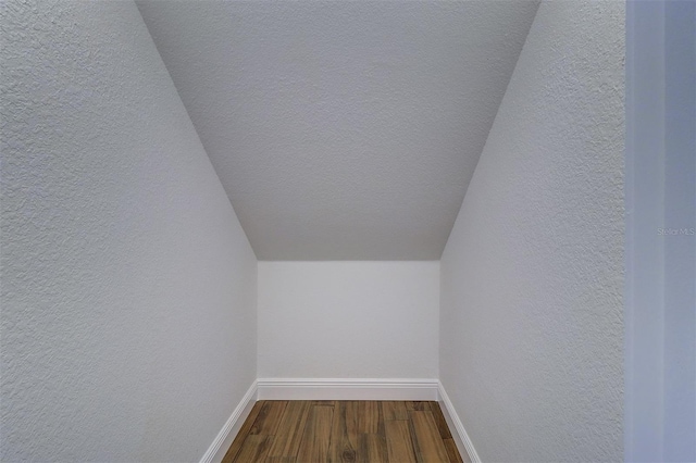 5449 Manatee Point Dr, New Port Richey, FL 34652 - additional living space with dark wood-type flooring, a textured wall, and vaulted ceiling